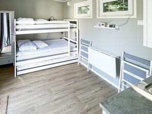 A bunk bed room with a desk and shelves, wooden flooring, and a window with a view of greenery. - 3 Person Holiday Home in Ljungby (Ljungby)