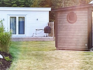 A residential property with a white house, a wooden shed, and a lawn. - 3 Person Holiday Home in Ljungby (Ljungby)