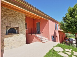 Un edificio de piedra con chimenea, una escalera y una pared exterior roja.
