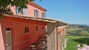 Un edificio rojo con un patio, una mesa de comedor y bancos.