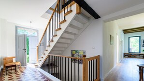 A staircase with wooden steps and black railings, leading to a landing with a patterned floor.