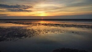 A beach at sunset with calm waters reflecting the sky. - Sun, Mudflats and sea (Wurster Nordseeküste)