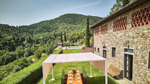 A stone building with a covered outdoor dining area, a pool, and a lush green landscape. - Farmhouse in Chianti With Pool and Garden (Cavriglia)