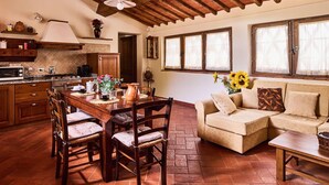 A cozy kitchen with a wooden table and chairs, a sofa, and a window with curtains. - Farmhouse in Chianti With Pool and Garden (Cavriglia)