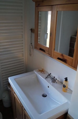 A bathroom with a white sink, wooden cabinets, and a mirror above the sink.