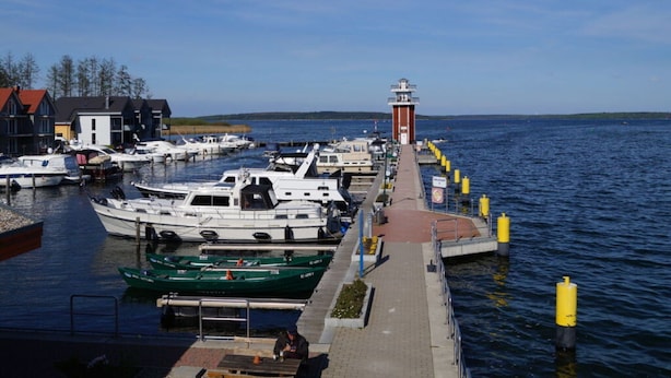 Satamassa on laivoja, majakka ja laituri, joka ulottuu veteen.