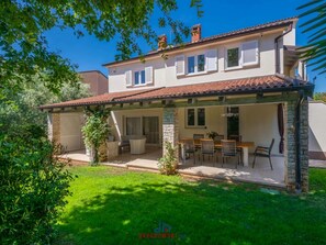 A two-story house with a covered patio, a dining area, and a garden. - Villa Regenboog (Porec)