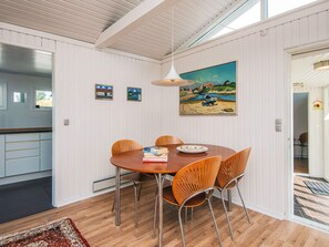 A dining area with a round table, six chairs, and a painting on the wall.