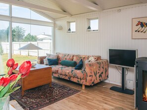 A cozy living room with a sofa, a wooden coffee table, a TV, and a fireplace.