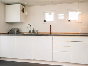 A kitchen with white cabinets, a toaster, a sink, and two pendant lights.