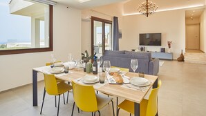 Ein moderner Essbereich mit einem Holztisch, gedeckt für vier Personen, gelben Stühlen und einem grauen Sofa im Hintergrund.