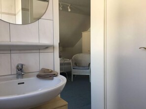 Un baño con lavamanos, espejo y toalla blancos.