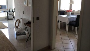 A hallway leading to a dining area with a table set for two, a radiator, and a black metal bench. - Holiday Apartment Helde Hochberg (Sasbach am Kaiserstuhl)