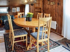 A wooden dining table with six chairs, surrounded by a patterned rug and a potted plant. - 4 Star Holiday Home in Berg I Ostfold (Halden)