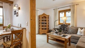 A cozy living room with a wooden coffee table, a sofa, and a wooden cabinet with glass doors. - Kehlstein - Reich Family (Schoenau am Koenigssee)