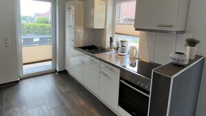 Cocina moderna con armarios blancos, estufa de acero inoxidable y ventana con persianas.