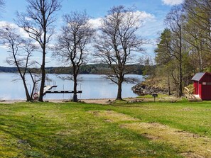 Une vue sur le lac, avec un quai, des arbres et un bâtiment rouge.
