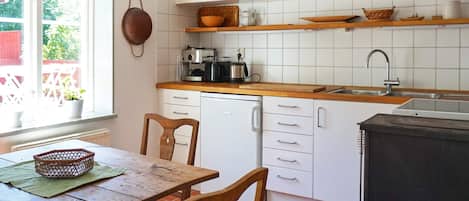 A kitchen with white cabinets, a wooden countertop, a sink, and a dining table with chairs.