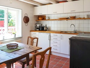 A kitchen with white cabinets, a wooden countertop, a sink, and a dining table with chairs. - 4 Person Holiday Home in Hedekas (Hedekas)