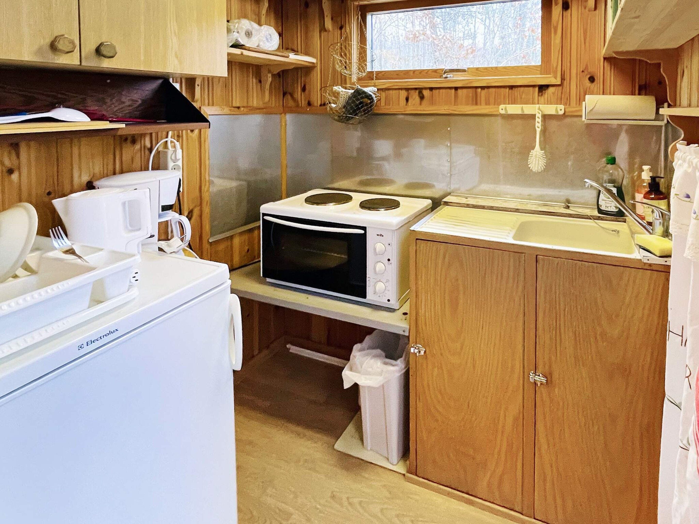 Une cuisine compacte équipée d’un four à micro-ondes, d’une cuisinière, d’un évier et d’un petit réfrigérateur.