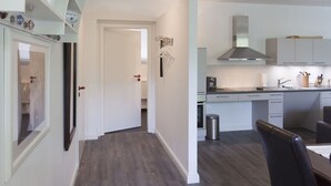 Eine moderne Küche mit weißen Schränken, einer Edelstahl-Dunstabzugshaube und einem Essbereich mit einem dunklen Holztisch und Stühlen.