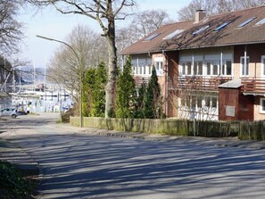 A residential building with a sloped roof, a fenced yard, and a street in the background.