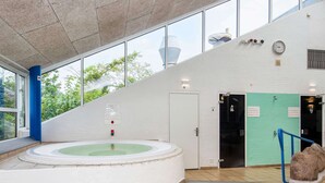 Een modern binnenzwembad met een whirlpool, een trap en uitzicht op het buitengebied.