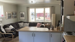 Un espacio habitable compacto con kitchenette, un sofá, una mesa de comedor y una silla.
