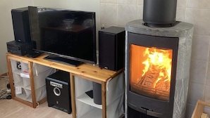 Una sala de estar con televisor, parlantes y estufa de leña.