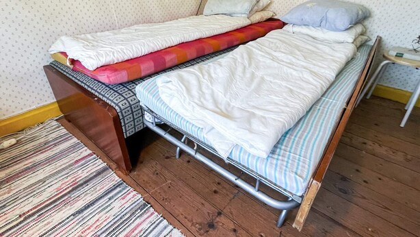 A small, single-bed room with a wooden floor, a striped rug, and a patterned wall. - 4 Person Holiday Home in Solvesborg-by Traum (Sölvesborg)