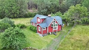 A red house with a sloped roof, surrounded by green grass and trees. - 4 Person Holiday Home in Solvesborg-by Traum (Sölvesborg)