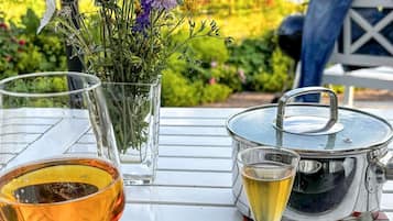 A table with a glass of beer, a glass of white wine, a pot, and a vase with flowers.