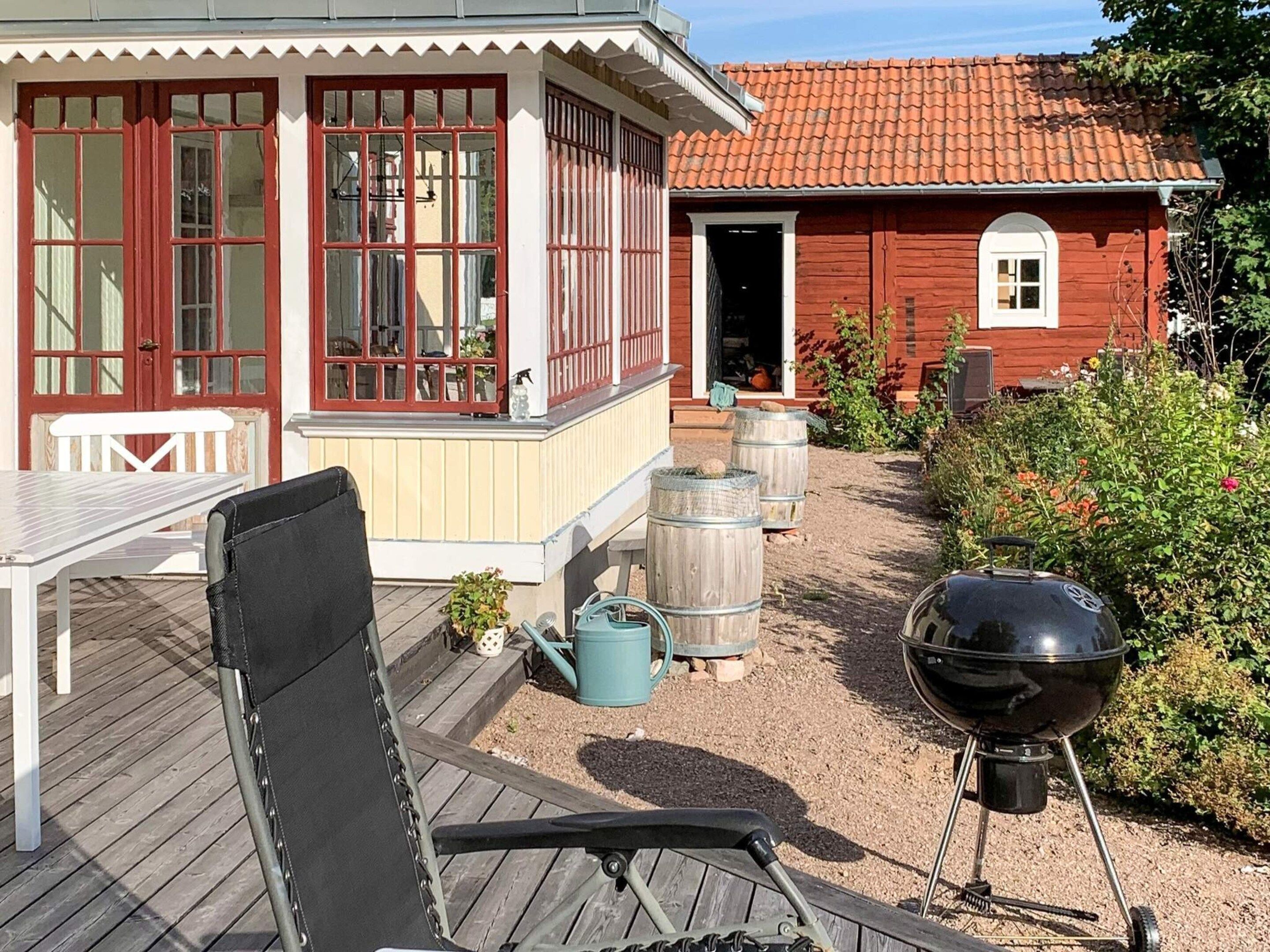Ein Holzhaus mit rotem Ziegeldach, einer Veranda und einem Grill.
