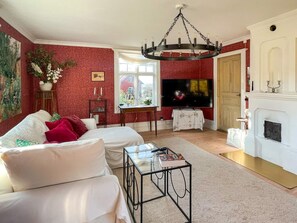 Un salon avec un canapé blanc, une table basse en verre, un téléviseur et une cheminée.