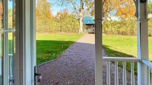 Een overdekte doorgang naar een gebouw met een groen dak, omgeven door bomen en een gazon.