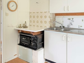 A kitchen with a vintage stove, a sink, and a clock on the wall. - 6 Person Holiday Home in Henan (Henån)