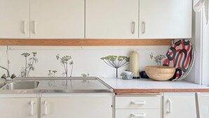 Een keuken met witte kastjes, een houten aanrecht en een roestvrijstalen spoelbak.