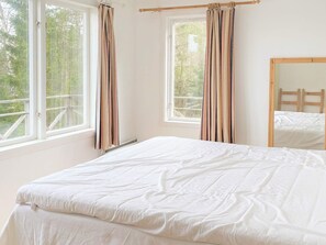 A bedroom with a bed, two windows with curtains, and a view of trees outside. - 6 Person Holiday Home in Henan (Henån)