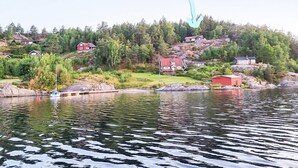 A lakeside property with houses on a hillside, a dock, and a boat.