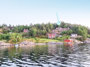 En fastighet vid en sjö med hus som ligger på en sluttning, en brygga och en båt.