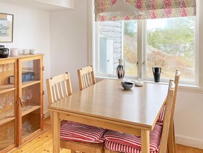 A dining area with a wooden table, four chairs, a cabinet with glass doors, and a window with a view of trees. - 6 Person Holiday Home in Henan (Henån)