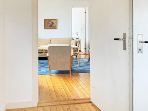 Une pièce avec un plancher en bois, une chaise, un lit et une porte.
