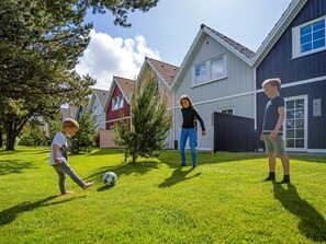 Un quartier résidentiel avec des maisons, une pelouse et un ballon de foot.
