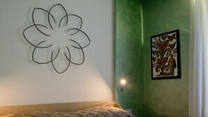 Quarto com cama, decoração de flores na parede e uma obra de arte emoldurada.