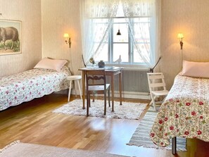 A room with two single beds, a wooden table, a chair, a radiator, and two wall-mounted lamps. - 4 Person Holiday Home in Vimmerby (Vimmerby)
