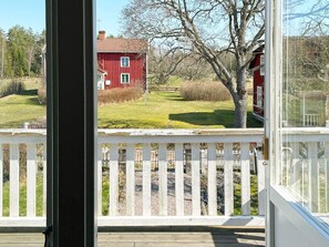 A wooden deck with a white railing, a red house in the background, and a clear sky. - 4 Person Holiday Home in Vimmerby (Vimmerby)