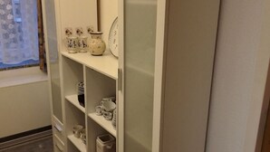 A white wardrobe with shelves containing various kitchenware and a clock. - Saalendorf - Holidays (Grossschoenau)