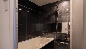 A modern bathroom with a freestanding bathtub, a glass shower enclosure, and a mirror above the sink. - XcellHIROSHIMA HEIWAODORI (Hiroshima)