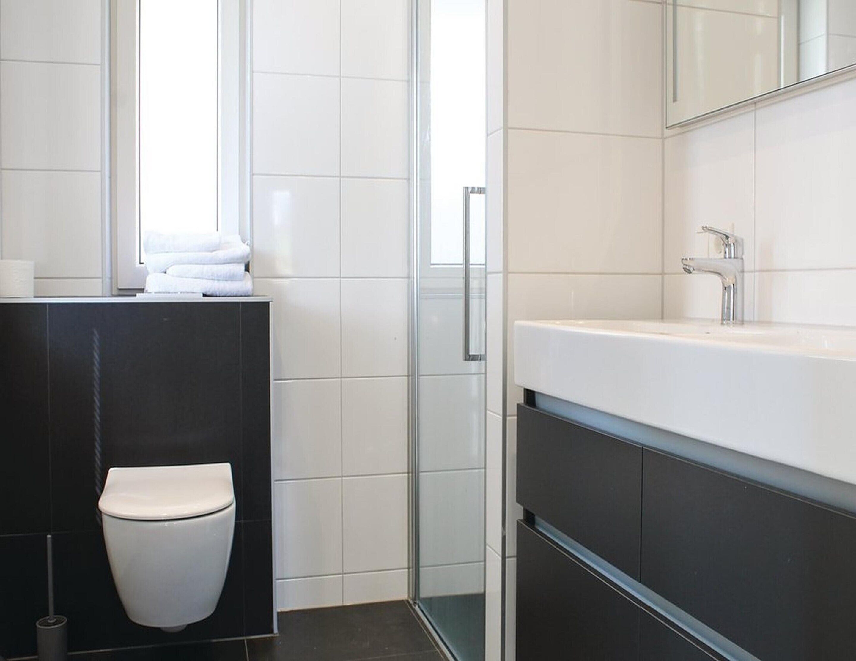 A modern bathroom with a toilet, a sink, and a mirror.