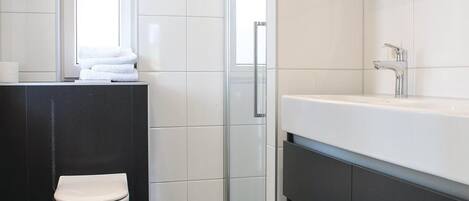 A modern bathroom with a toilet, a sink, and a mirror.